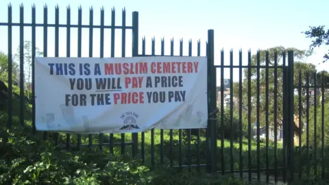 BBC A protest sign outside a cemetery