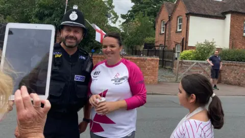 Baton bearer poses with a police officer in Upton-upon-Severn