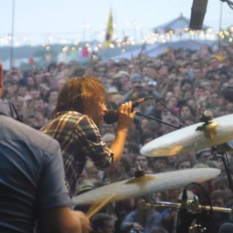 Russ Hollowell Singer on stage with cymbals in the foreground