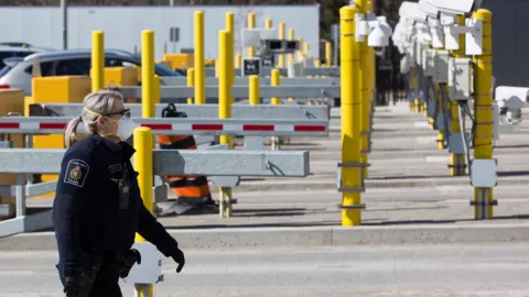 Getty Images A Canadian border officer wears as face mask at the US/Canada border in Lansdowne, Ontario, on March 22, 2020.