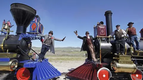 Getty Images Men re-enact the historic Champagne Toast with the Jupiter (L) and the 119 steam engines meet on the railway line