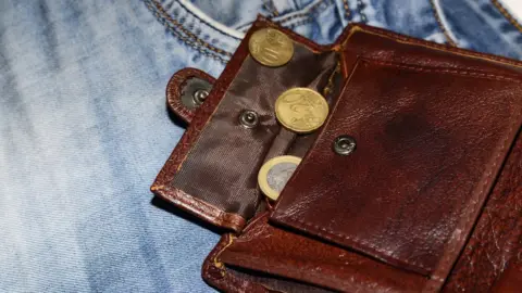 Getty Images A wallet with money spilling out