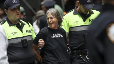 Getty Images A protestor is arrested by NYPD officers after staging a protest near the Wall Street Bull