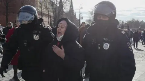 EPA A woman being led away in Moscow