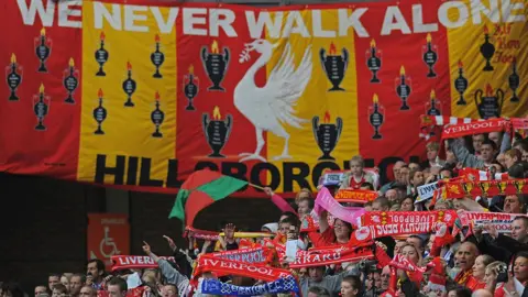 Getty Images Peter Carney's We Never Walk Alone banner hangs from a stand at Anfield during the memorial service on 15 April 2009 marking the 20th anniversary of the Hillsborough disaster