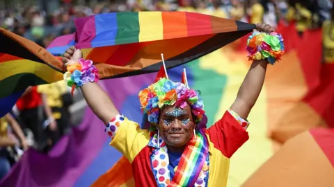 A person holds up a Pride flag in London