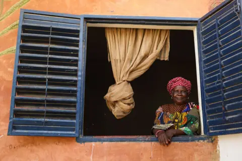 CEM OZDEL/GETTY IMAGES A woman looks out of the window of a house.