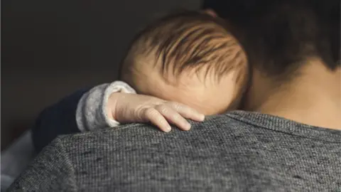 A one-month-old boy on his father's shoulder