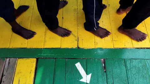 Migrants wait to disembark from the Vos Hestia ship as they arrive at the Crotone harbour