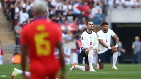 Getty Images Jordan Henderson and Tyrone Mings taking a knee before England v Andorra
