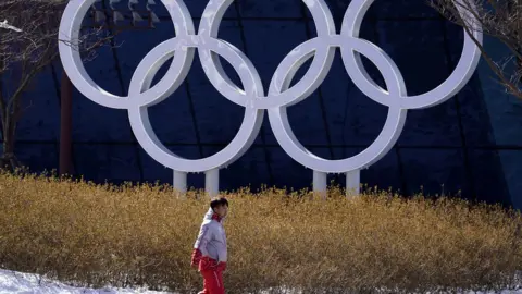 EPA A volunteer walks past the Olympics Rings installation at the Olympic Village