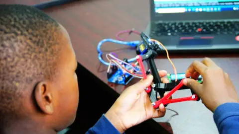 BBC/Peter Njoroge A child with a model at the Stem Impact Centre in Nairobi, Kenya