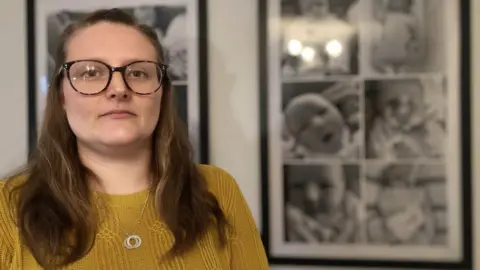 Alex Dunlop/BBC Natalie Lockyer standing in front of a compilation picture of her daughter Quinn