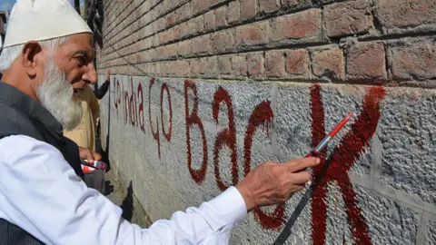 Getty Images Geelani writes anti-India graffiti on a wall in Kashmir