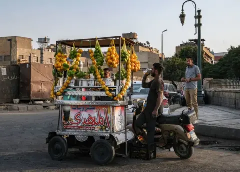 AFP A man drinking juice at a vendor's stall.