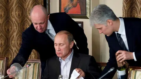 Reuters Yevgeniy Prigozhin (L) assists Russian Prime Minister Vladimir Putin during a dinner with foreign scholars and journalists at the restaurant Cheval Blanc on the premises of an equestrian complex outside Moscow November 11, 2011