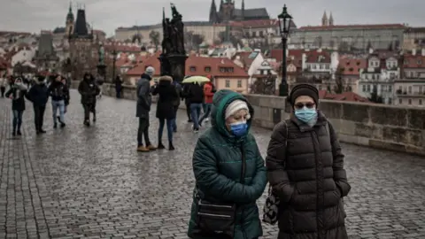 Getty Images Two women walk side by side in Prague wearing face masks