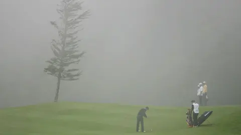 Getty Images Golfers play in foggy conditions.