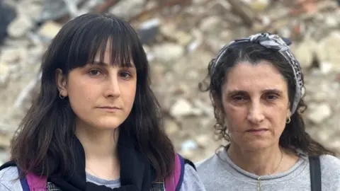 Orla Guerin/BBC Gozde Burgac and her aunt Suheyla Kilic, pictured in front of rubble in Antakya