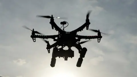 A drone silhouetted against the sky