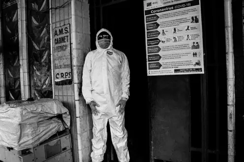 Justin Makangara for Fondation Carmignac A person wears Covid-19 protective overalls and mask