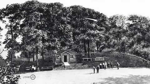 David Rowe Black and white photo show green in the foreground with people playing