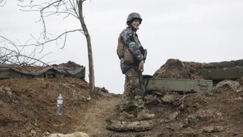 EPA A Ukrainian soldiers guards a defensive position in the Donbas