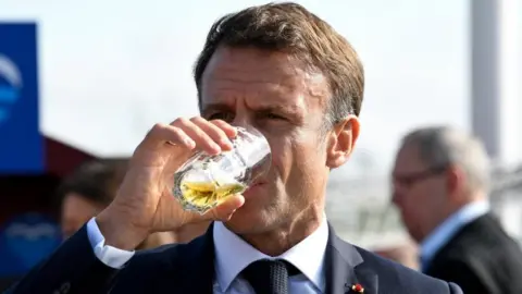 Reuters French President Emmanuel Macron drinks beer as he concludes a two-day government meeting in the northern German port city of Hamburg in October 2023