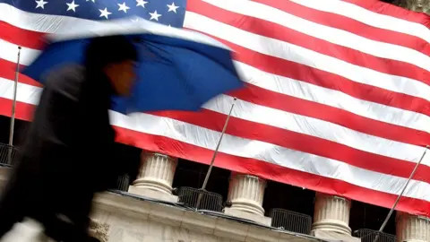 Getty Images US flag and pedestrian on Wall Street