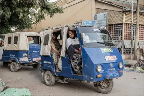 AFP A woman smiling in a blue taxi