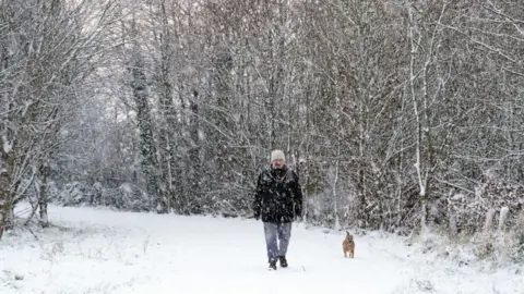 Owen Humphreys/PA Wire A man walks his dog in Gateshead as the snow continues to fall