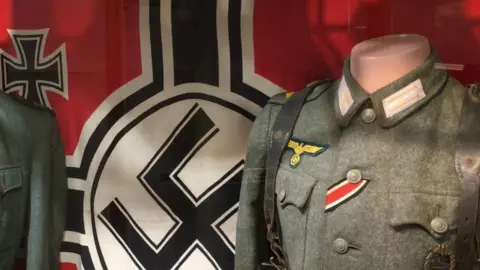 A Nazi swastika flag and uniforms on display in the Alderney Museum