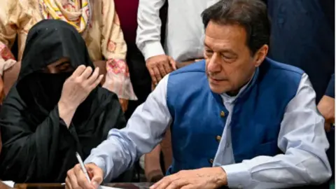 Getty Images Imran Khan and his wife Bushra Bibi sign surety bonds for bail in July 2023