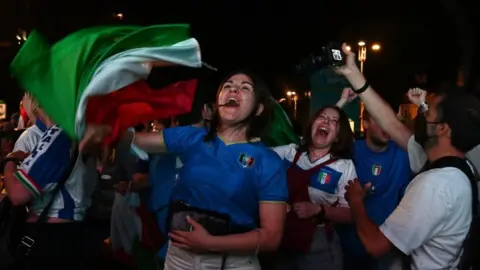 Getty Images Supporters of the Italian national football team celebrate after Italy beat England 3-2 on penalty shootout to win the the UEFA EURO 2020 final football match, at the Fori Imperiali fanzone, in Rome