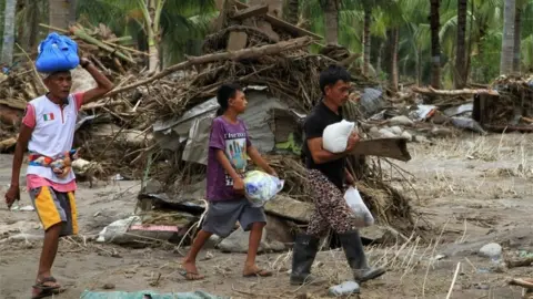 Reuters Residents in Salvador district with relief supplies after the devastating floods which hit Mindanao in the Philippines, 24 December 2017