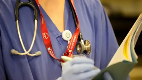 Getty Images An NHS nurse in an operating theatre at Birmingham Women's Hospital, 22 January 2015