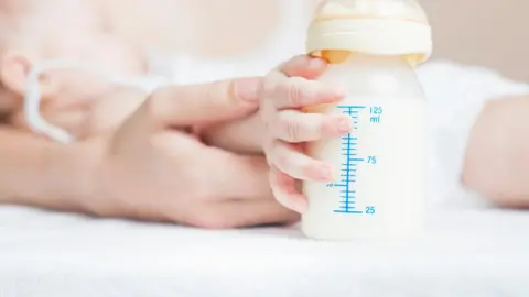 Getty Images Baby holding bottle