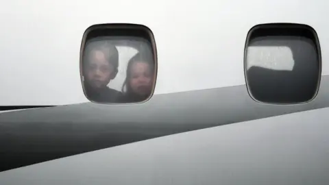 EPA Charlotte and George look out of the window of the plane before disembarking