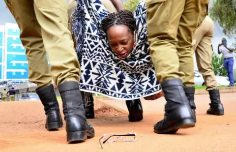 Reuters A woman looks back at her glasses as she is forcibly carried away by uniformed officers.