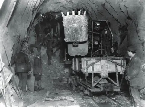 Alamy Black and white photo of workers digging a tunnel