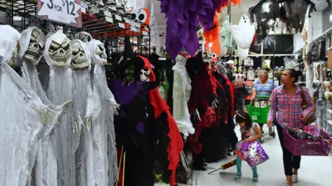 AFP/Getty Images A family walks down an aisle of Halloween costumes