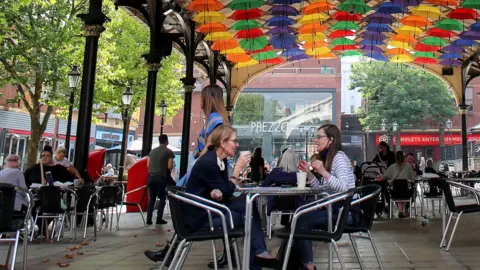 Reuters People socialise at an outdoor venue in Warrington