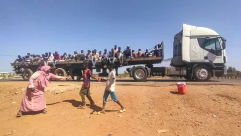 AFP People displaced by the conflict in Sudan ride on the back of a truck moving along a road in Wad Madani, the capital of al-Jazirah state