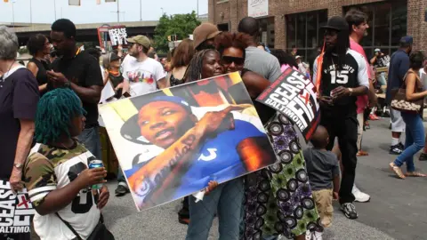 BBC Kim Ford carries a picture of her son, Troy Biggus, who was murdered when he was 21