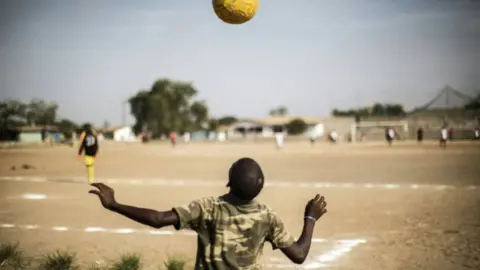 AFP A Liberian boy plays with a ball as international Liberian football star, George Weah plays a match on a dusty pitch at the Alpha Old Timers Sports Association in Paynesville in Monrovia on April 30, 2016