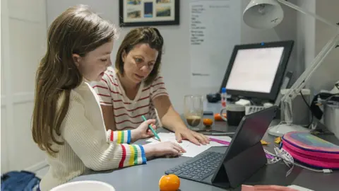 Getty Images A woman helping her daughter with school work