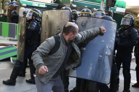 Zakaria Abdelkafi / AFP A man pushes scuffles with CRS anti-riot police