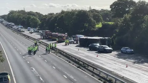 Emergency services attend an overturned bus on the M53