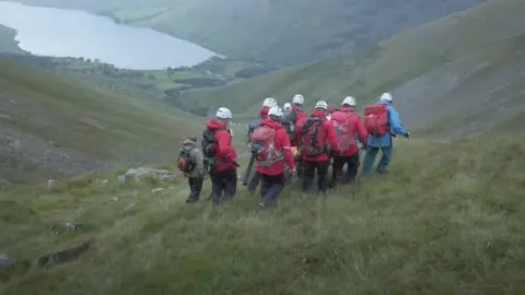 Wasdale MRT Six rescuers carry stretcher with Daisy on it overlooking lake