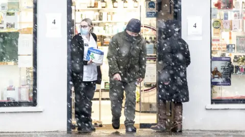 PA Media Sleet and snow fall outside Graeme Pharmacy in Biggar, South Lanarkshire as Storm Barra hits the UK and Ireland with disruptive winds, heavy rain and snow on Tuesday.